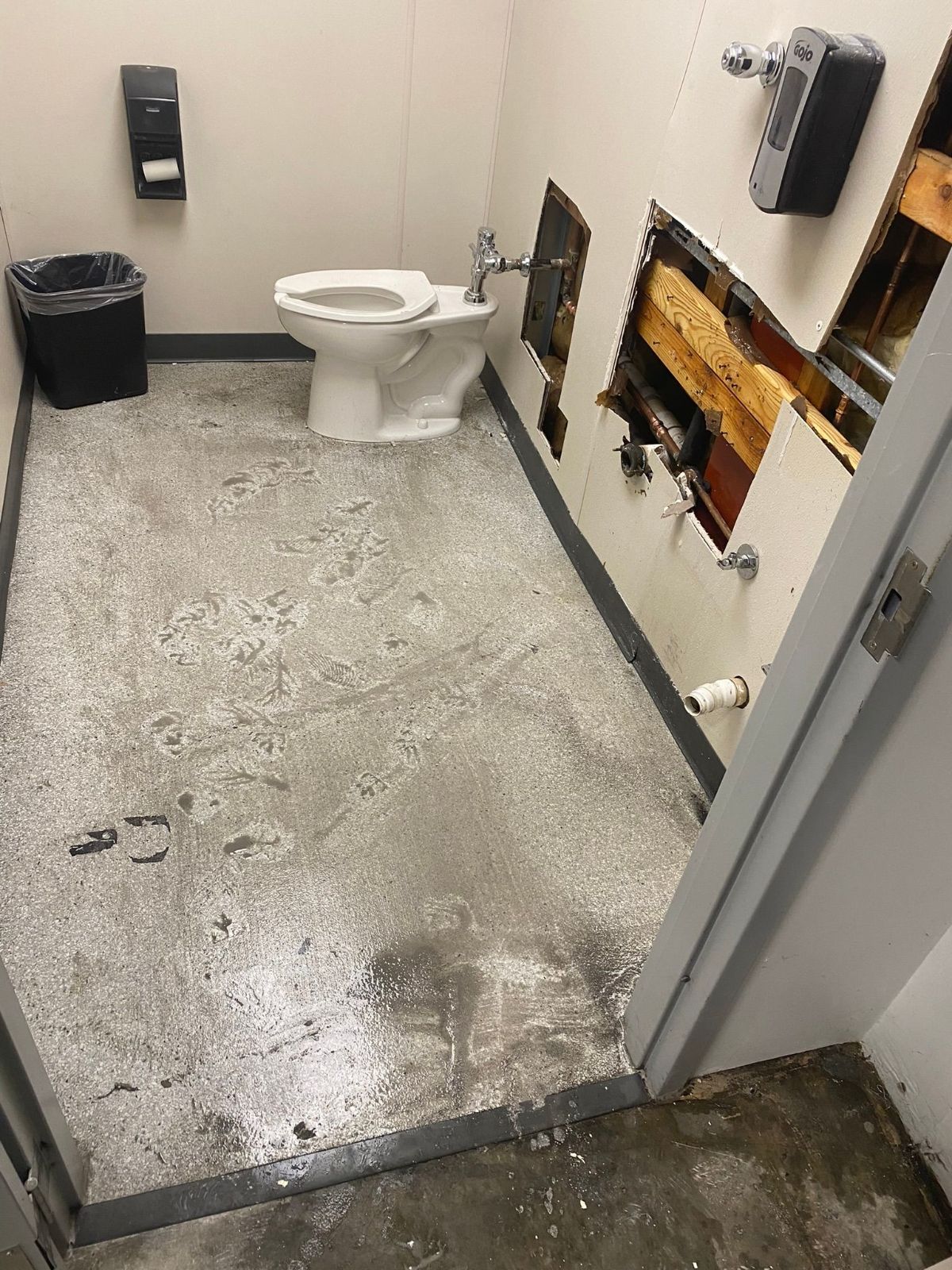 A bathroom with a toilet and a trash can in it.