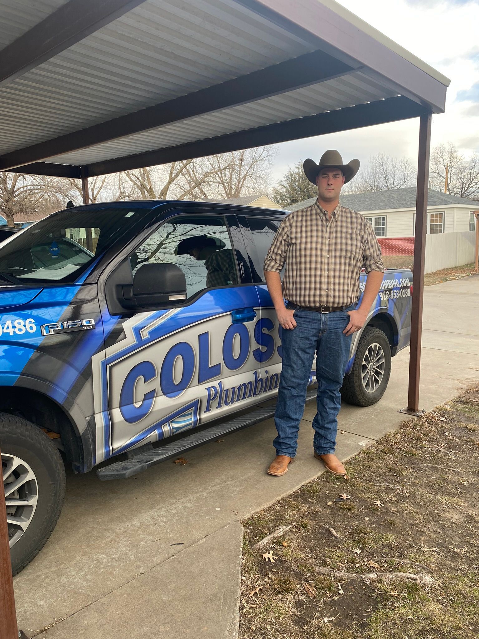 Man in cowboy hat stands by a blue truck with 