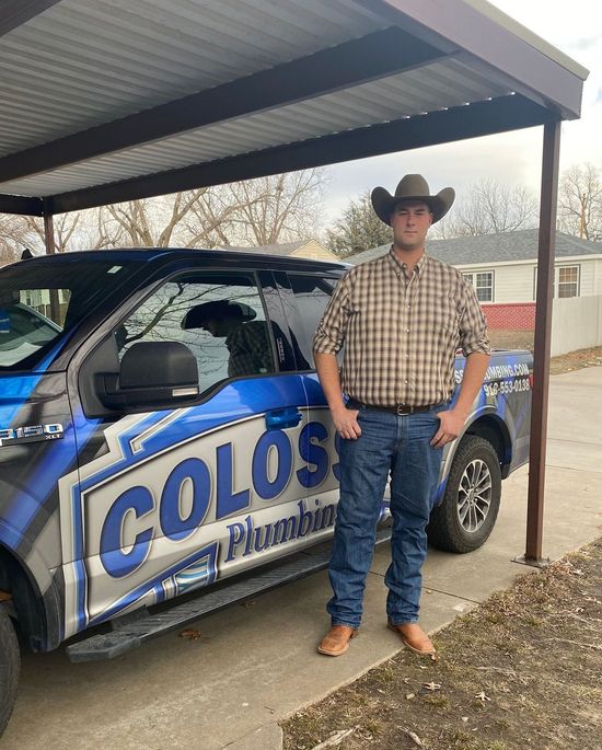 A man in a cowboy hat is standing in front of a truck.