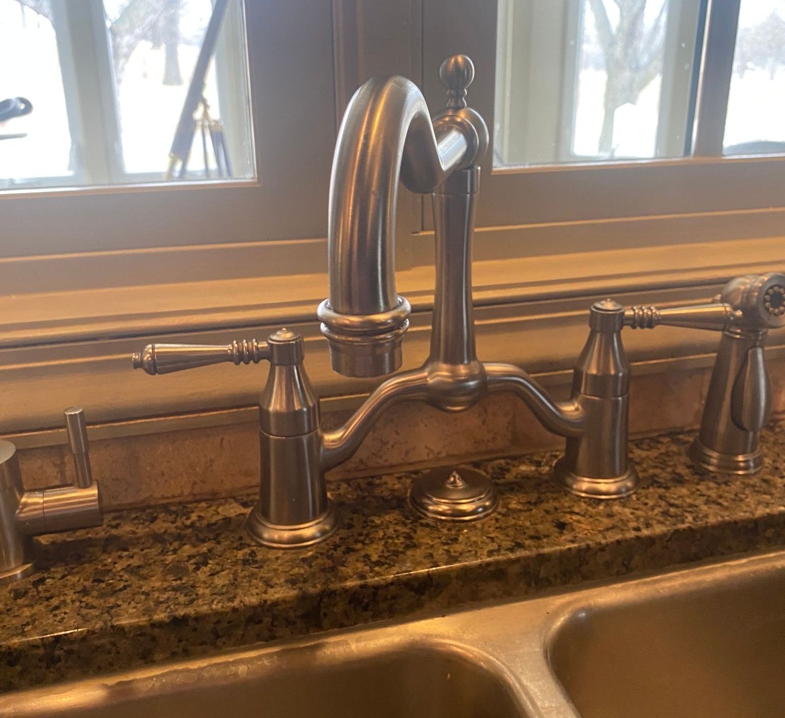 A kitchen sink with a faucet and a window in the background