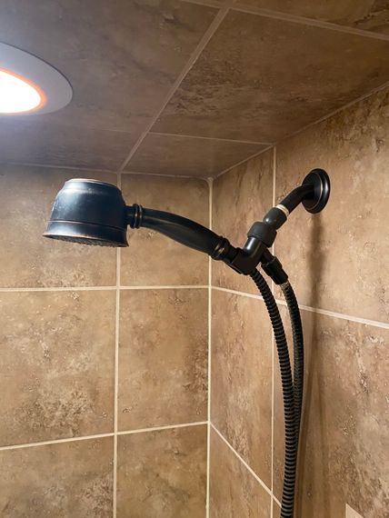 A shower head with a hose attached to it is hanging on a tiled wall.