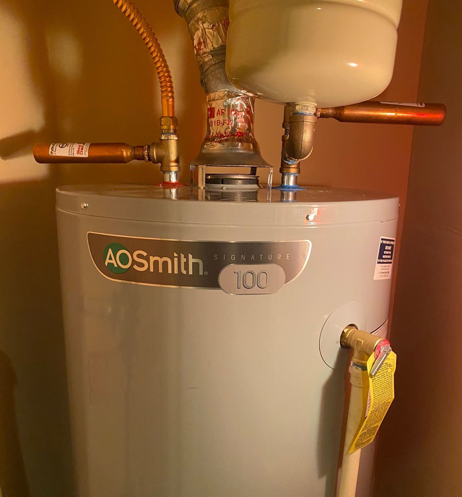 A white aosmith water heater is sitting next to a sink.