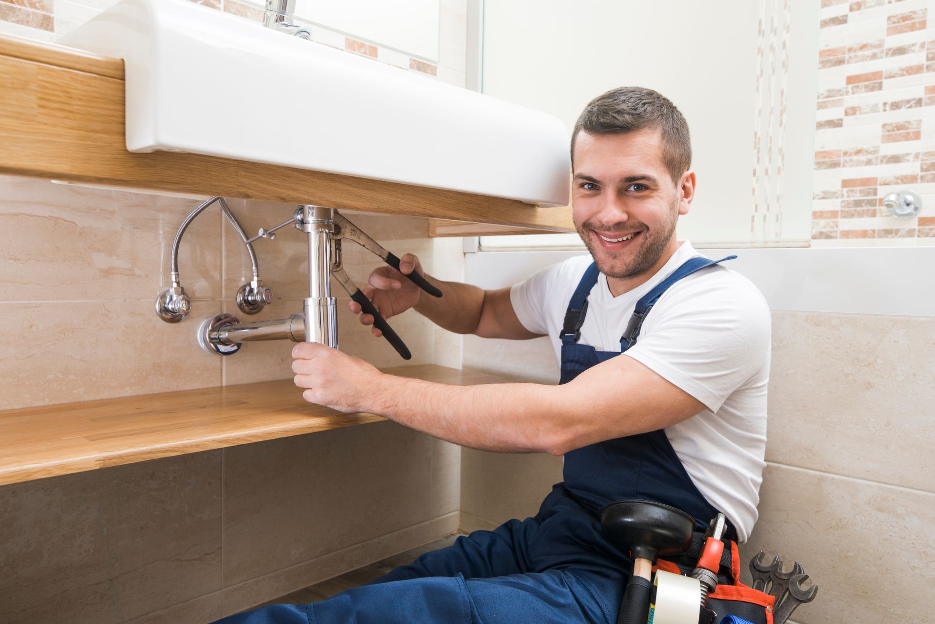 A plumber is fixing a sink in a bathroom.