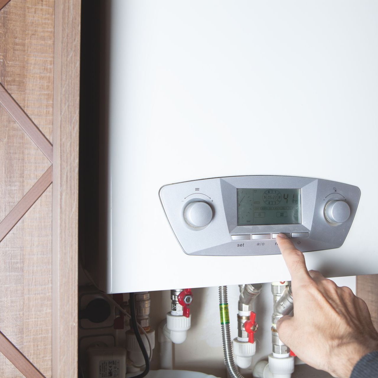 A person is pressing a button on a water heater.