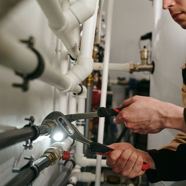 A man is working on a pipe with a wrench.