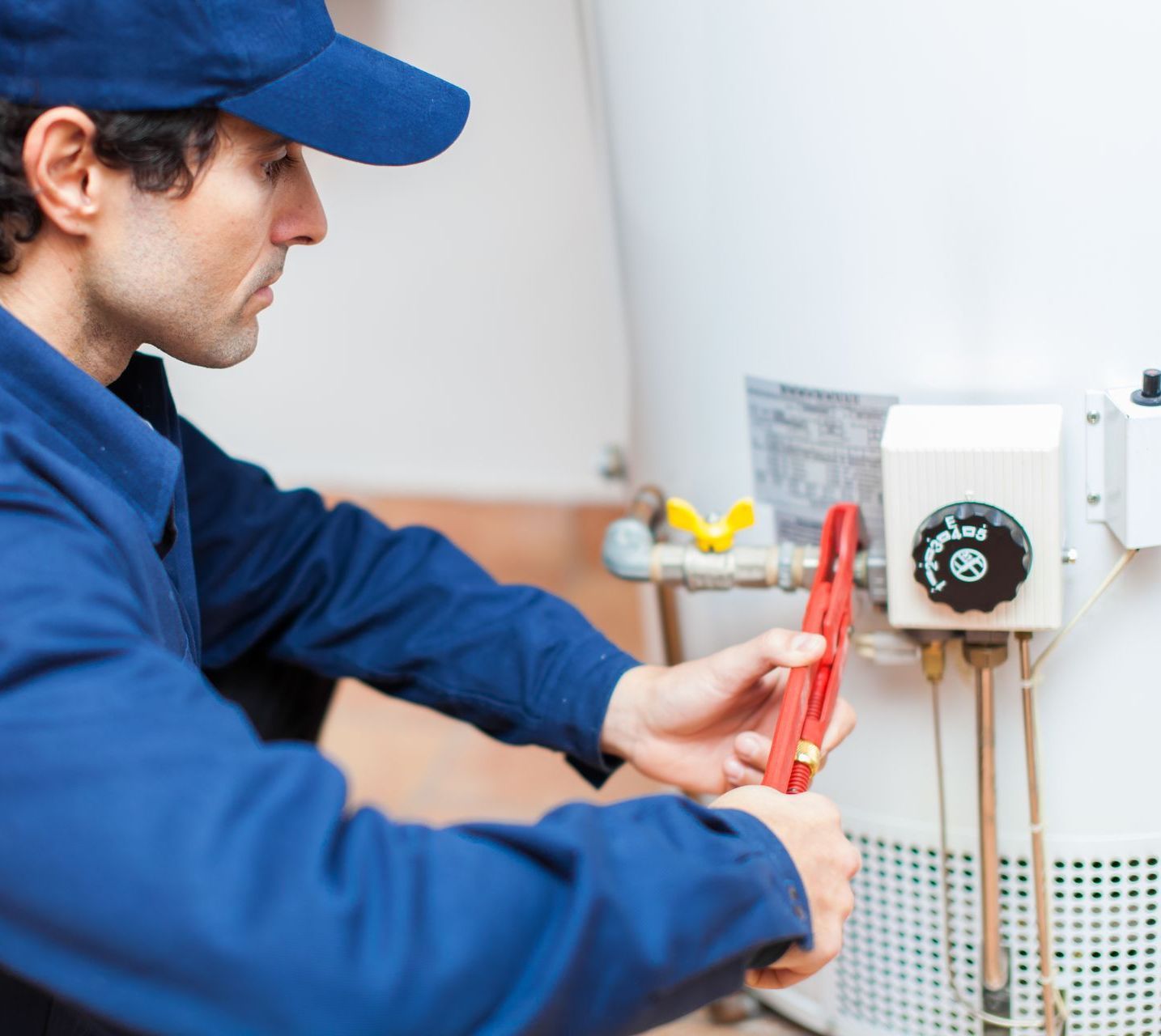 A man is fixing a water heater with a wrench