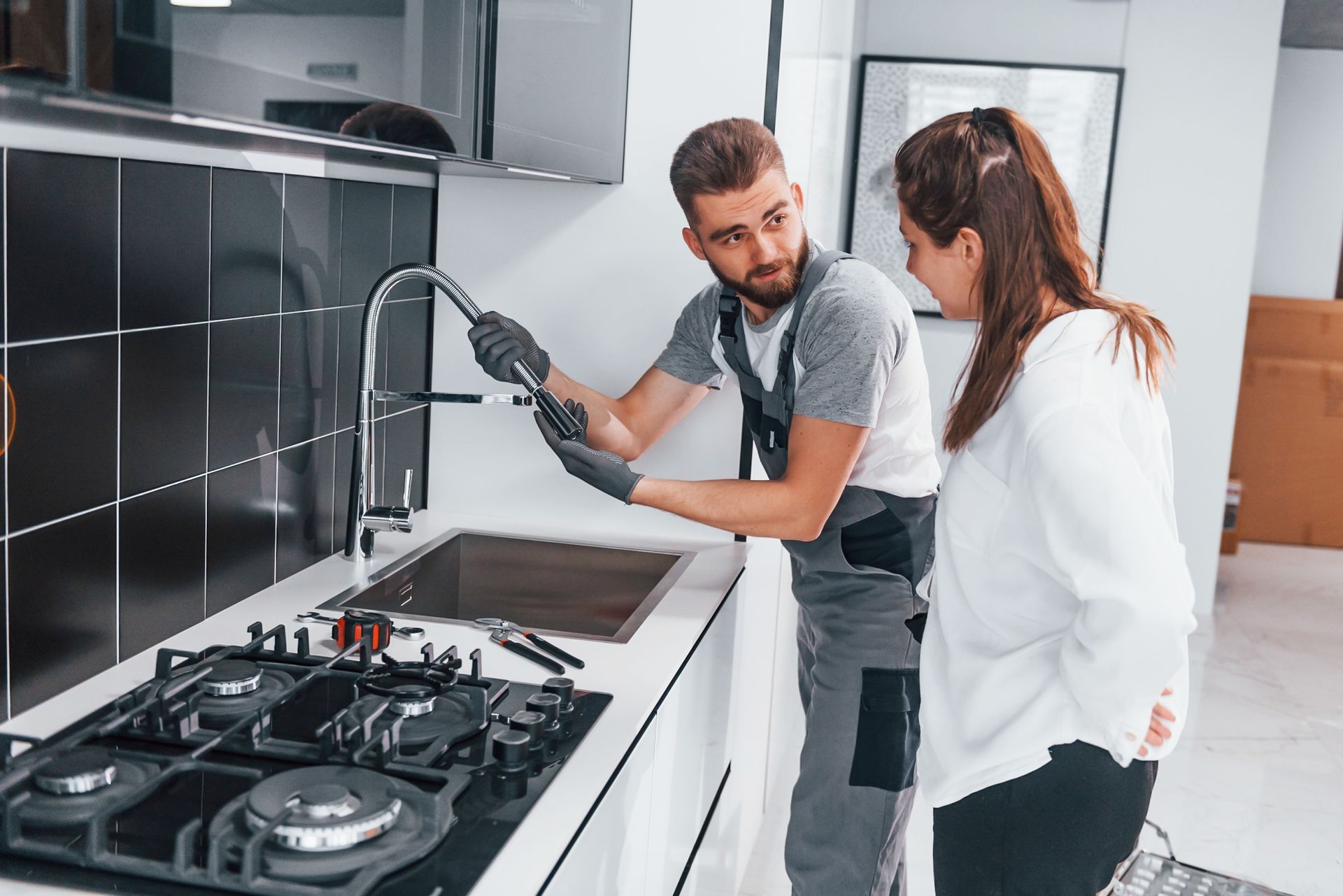 A man and a woman are looking at a faucet in a kitchen.