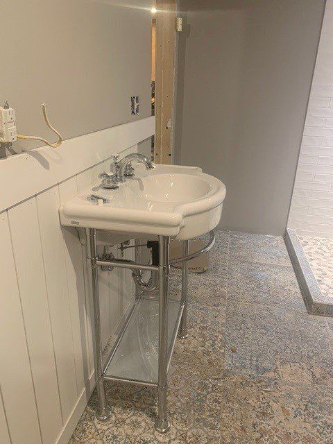 White pedestal sink in a bathroom with gray walls and patterned floor.