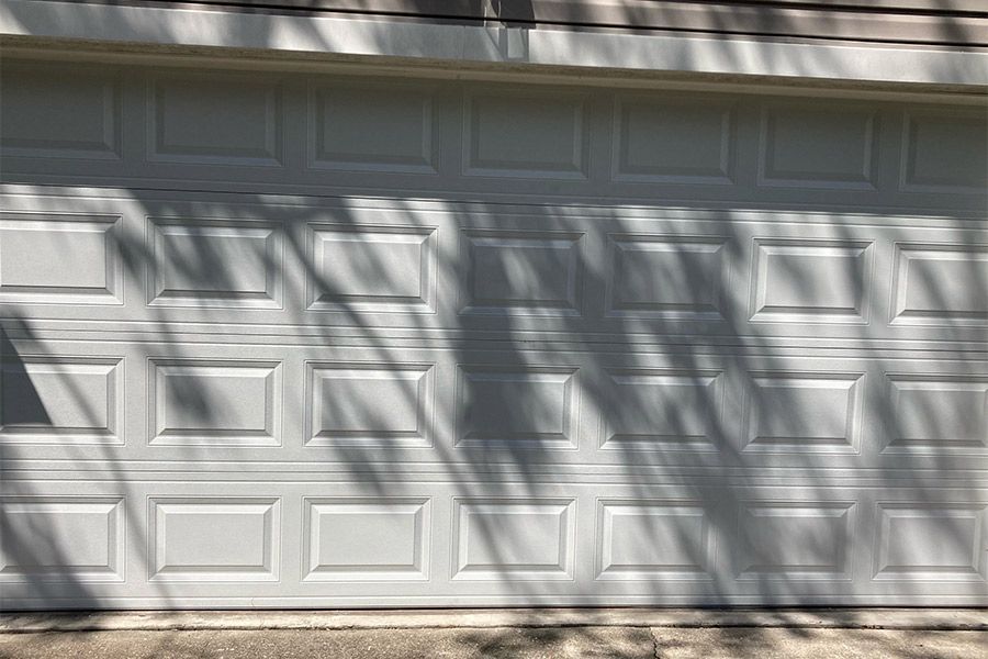 White garage door with shadows from trees overhead.