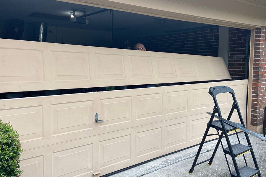 Beige garage door partially open, person visible. A step ladder is beside the door.