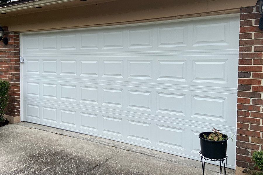 White garage door with panel design, set in brick building exterior.