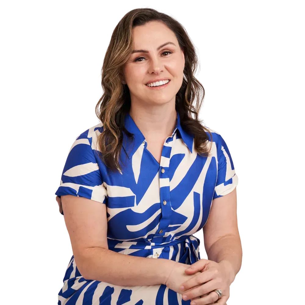Woman in a blue and white patterned dress, smiling, with hands clasped, on a white background.