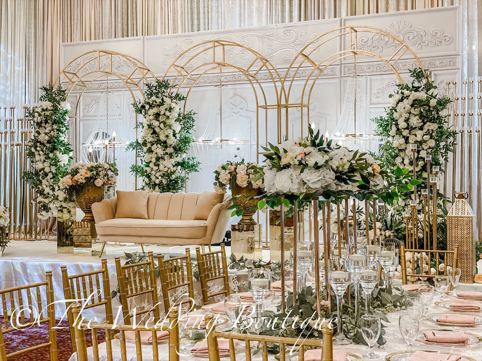 Gold chairs and dining table decorations spread out with flowers. The background shows a sofa on a wedding stage