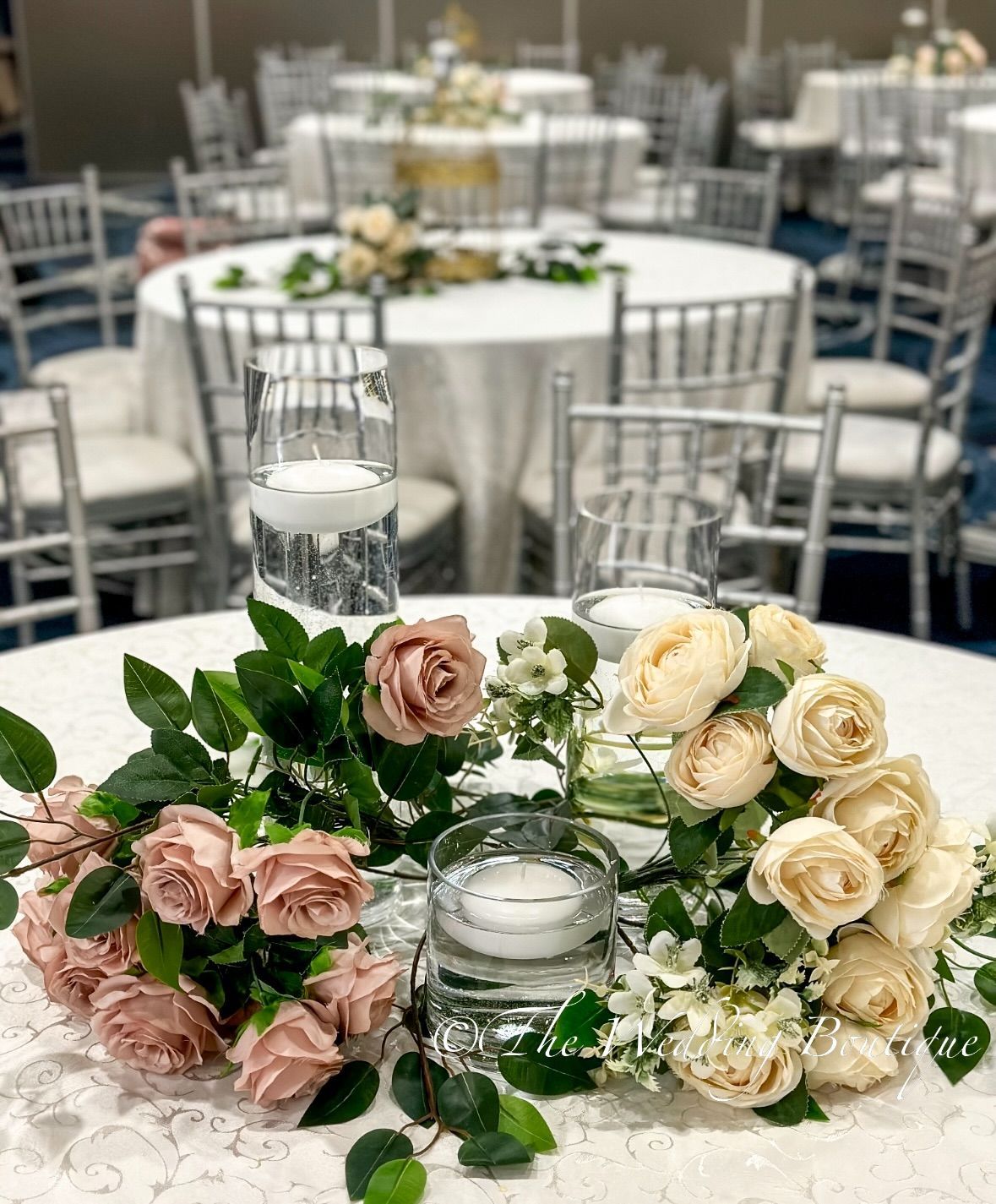 A dining table with glassware, candles, and flowers with a white tablecloth 