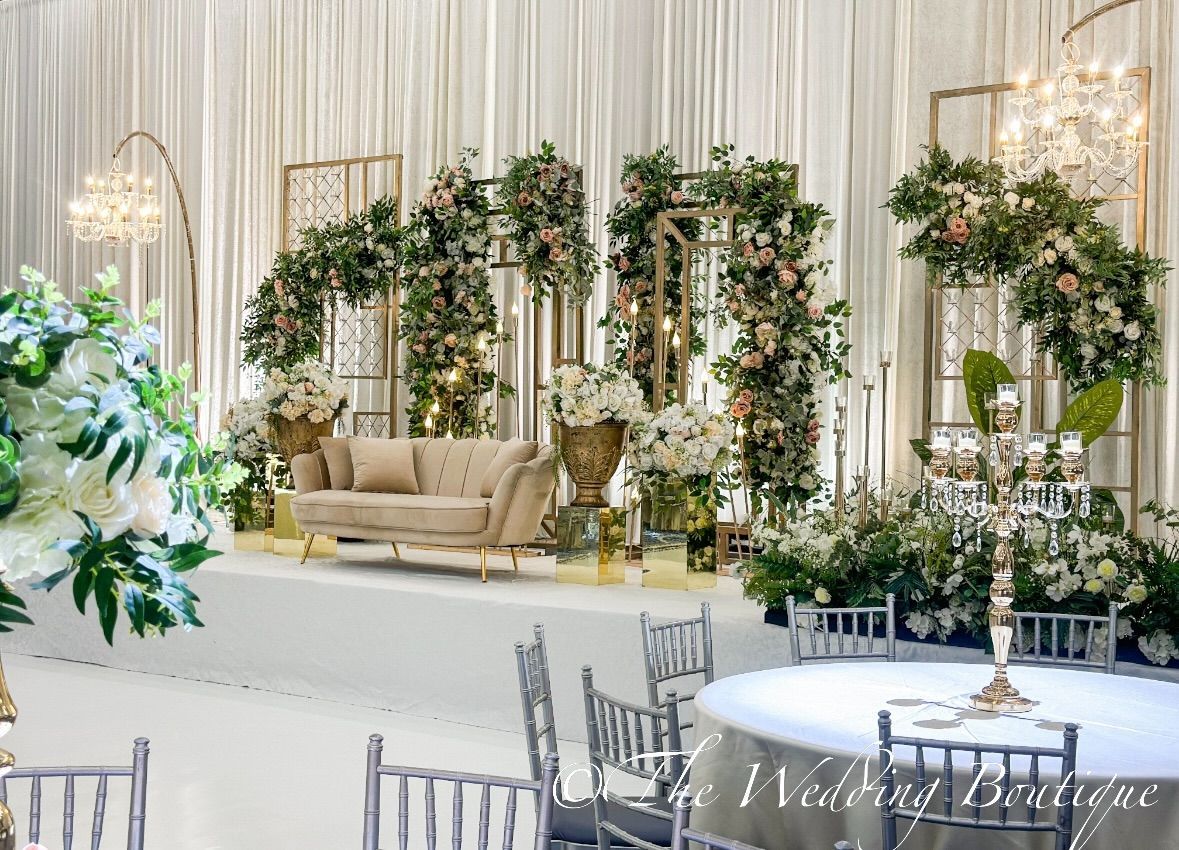 Bright and light wedding decor for reception hall featuring a sofa on a stage with dining tables in the foreground