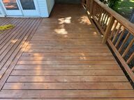 Wooden deck with railing, leading to a door of a building.