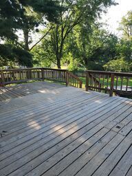 Wooden deck with railing, surrounded by trees.
