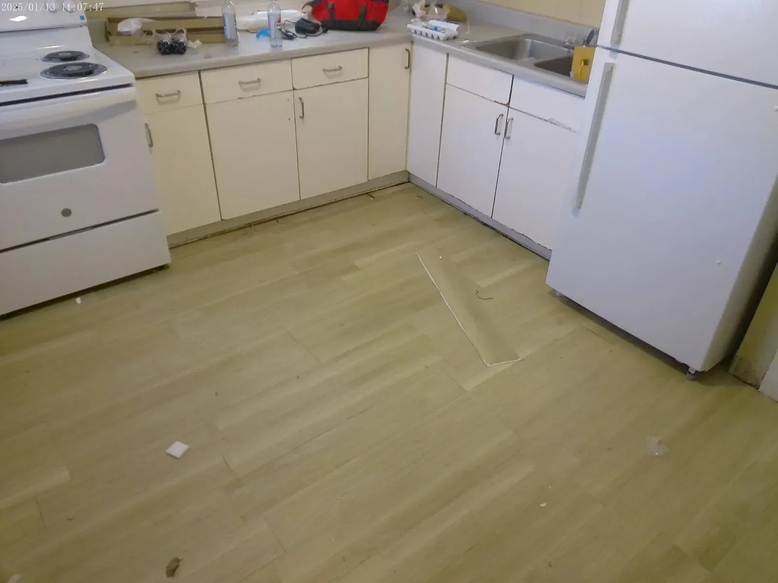 Kitchen floor repair in progress with vinyl plank damage and cabinet base updates