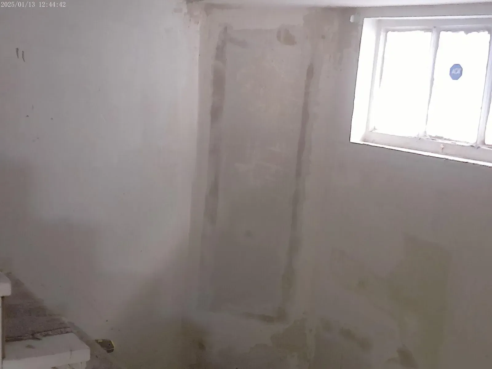 Drywall installation and patchwork near basement window during home renovation