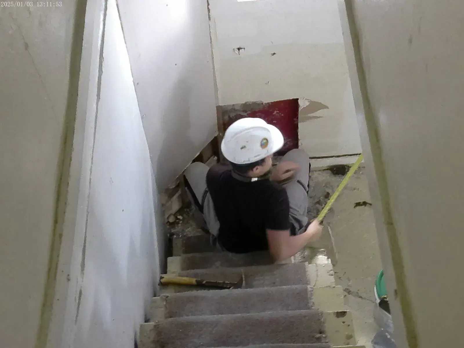 Handyman measuring for drywall repair and stair renovation project