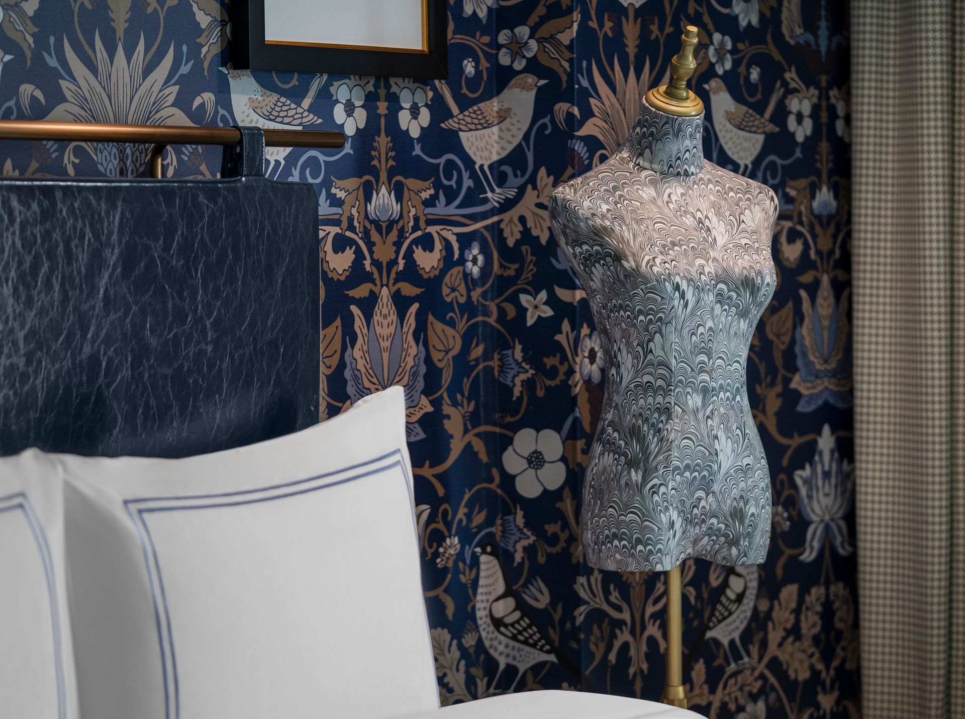 A mannequin is sitting on a bed next to a lamp.