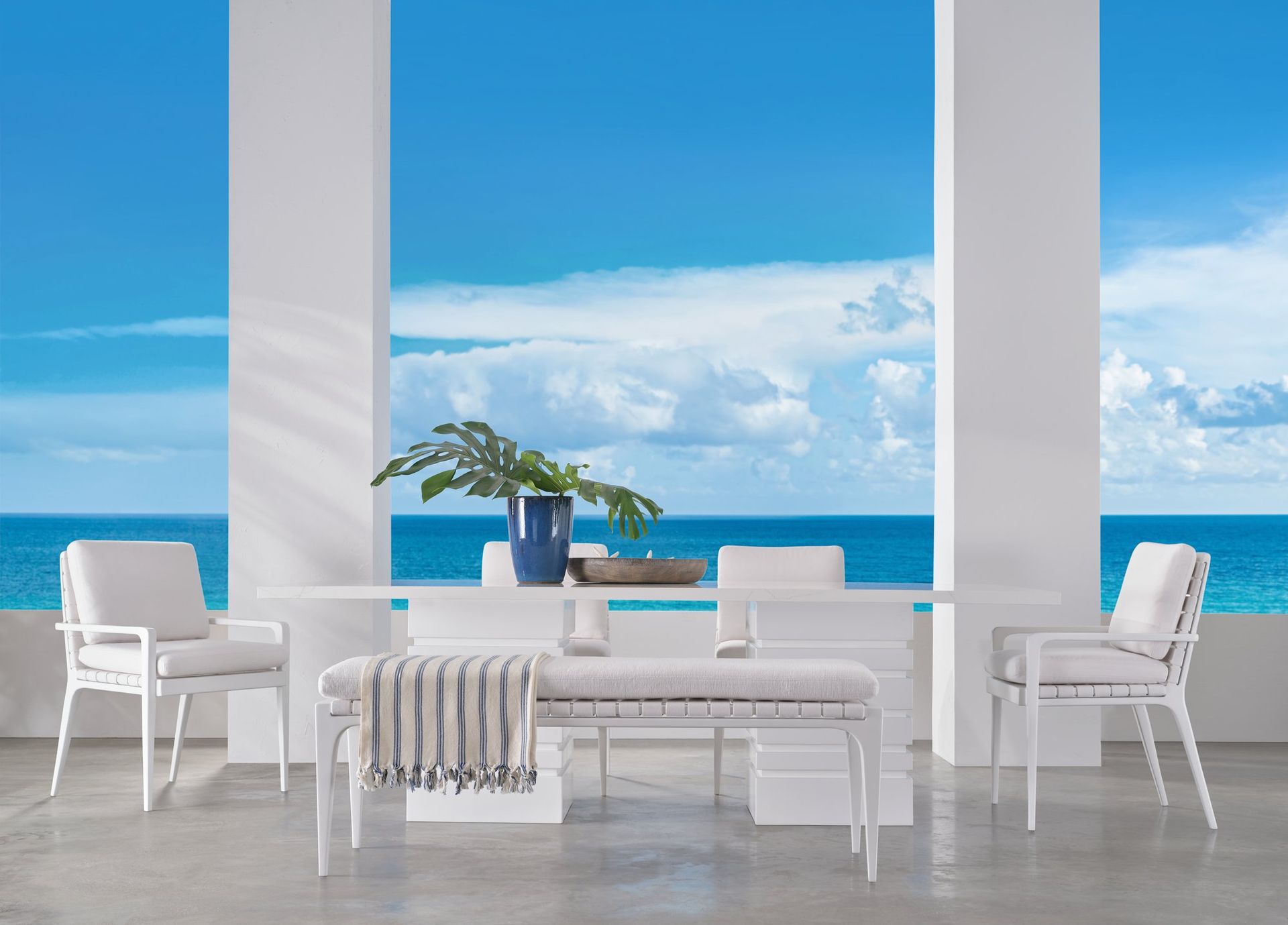 A table and chairs on a patio with a view of the ocean.