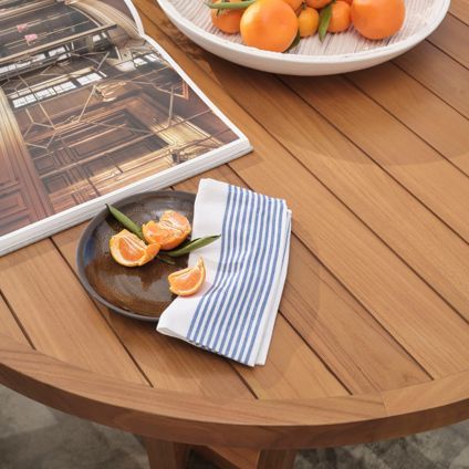 A wooden table with a plate of oranges on it