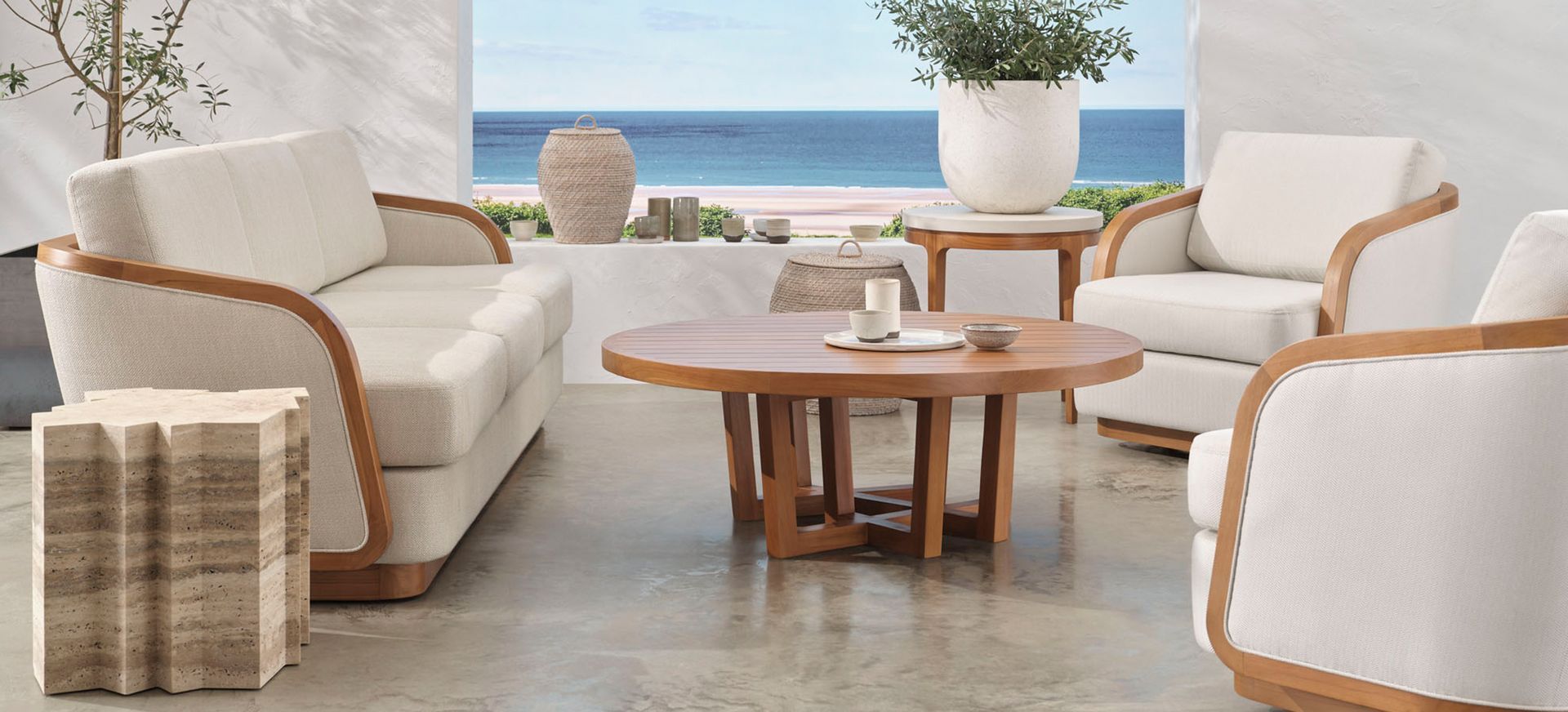 A living room with a couch , chairs , and a table with a view of the ocean.