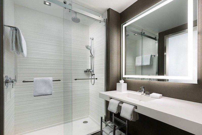 A bathroom with a walk in shower , sink and mirror.