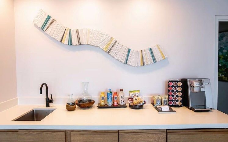 A kitchen with a sink , a coffee maker , and a painting on the wall.