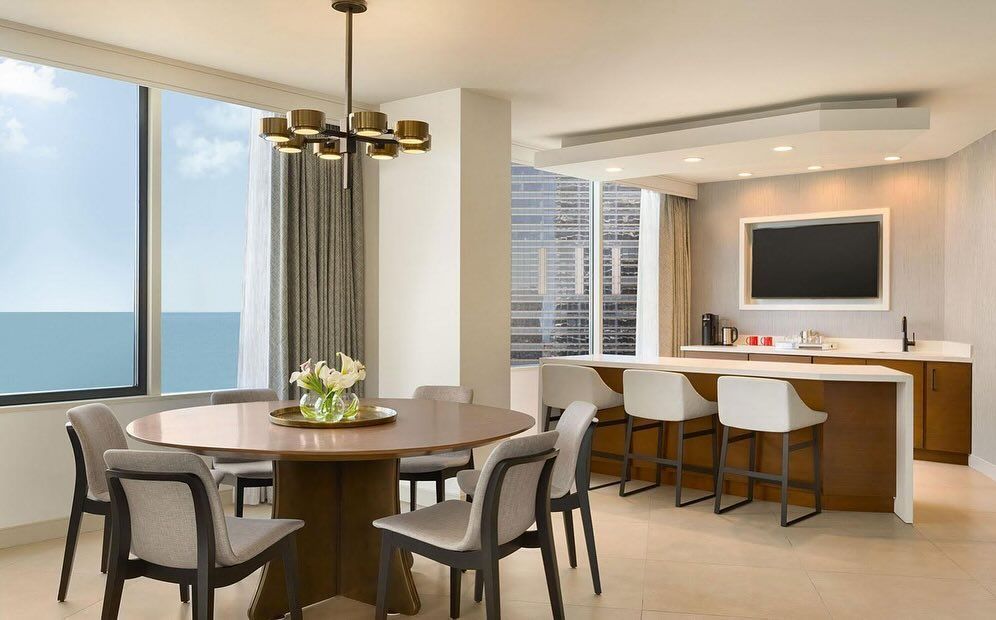 A dining room with a round table and chairs and a flat screen tv.