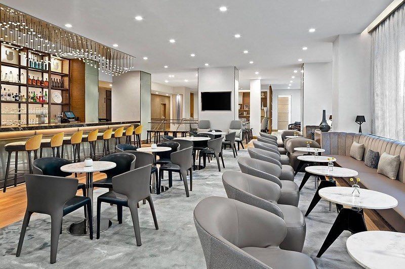 A hotel lobby with tables and chairs and a bar.