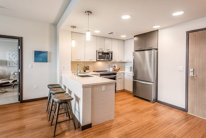 A kitchen with white cabinets , stainless steel appliances , a refrigerator and a sink.