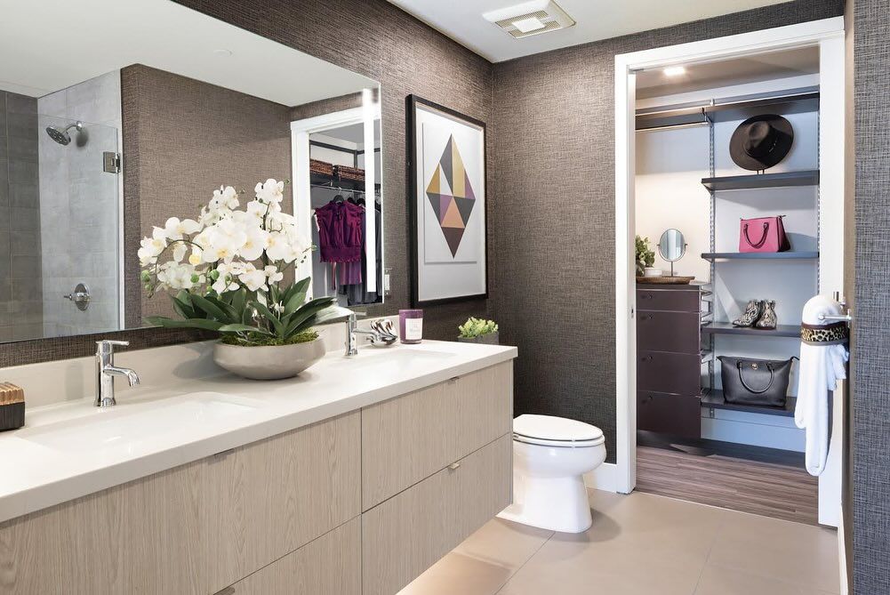 A bathroom with a sink , toilet , mirror and walk in closet.