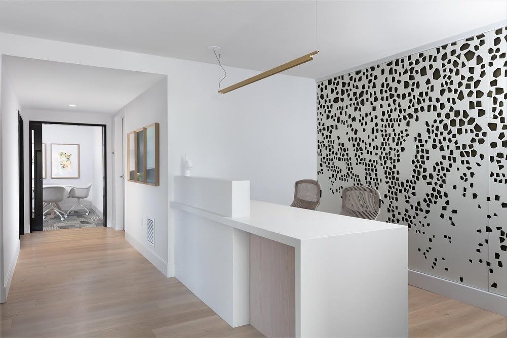 A reception area with a white counter and a black and white wall.