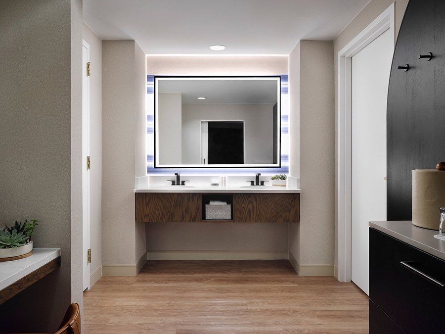 A bathroom in a hotel room with two sinks and a large mirror.