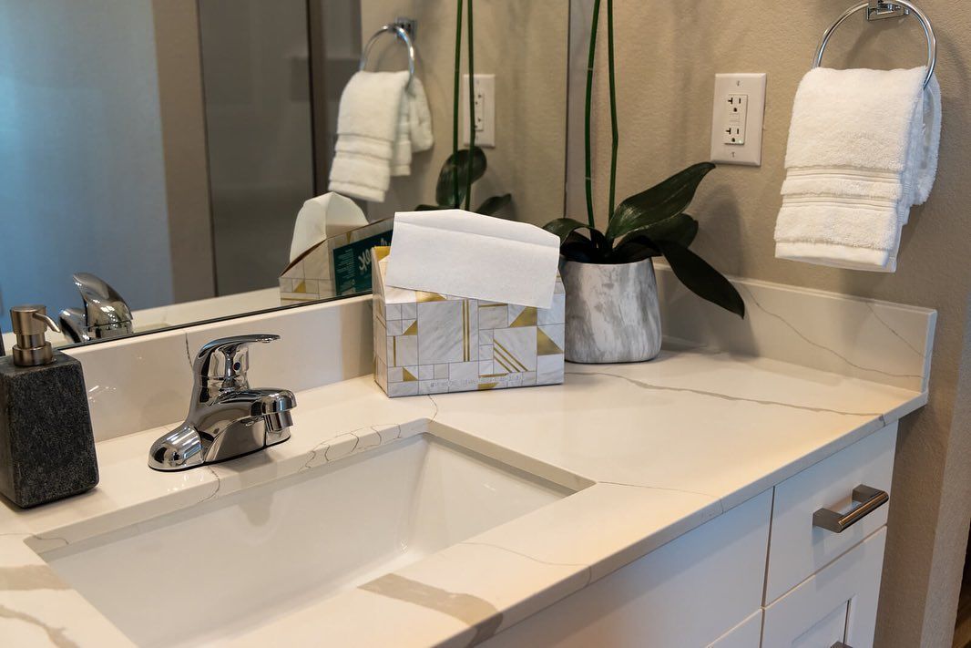 A bathroom with a sink , mirror and towels on the counter.