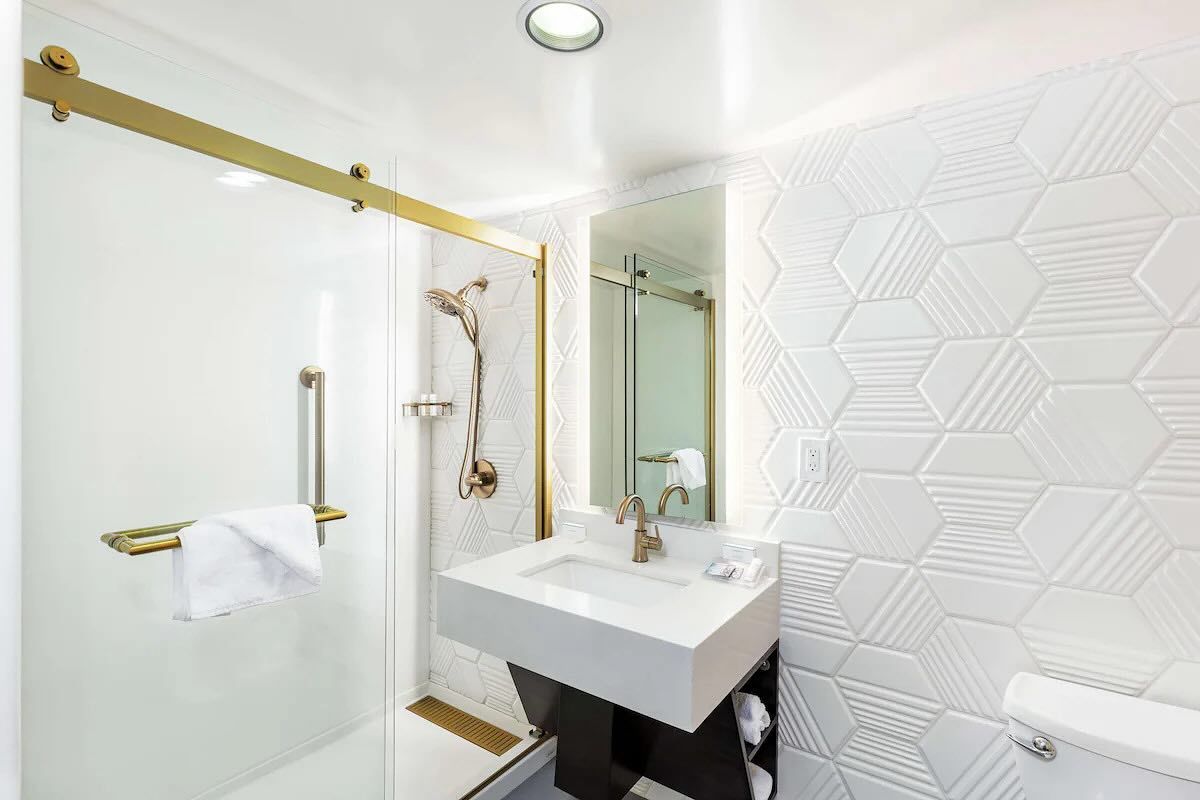 A bathroom with a sink , toilet , shower and mirror.