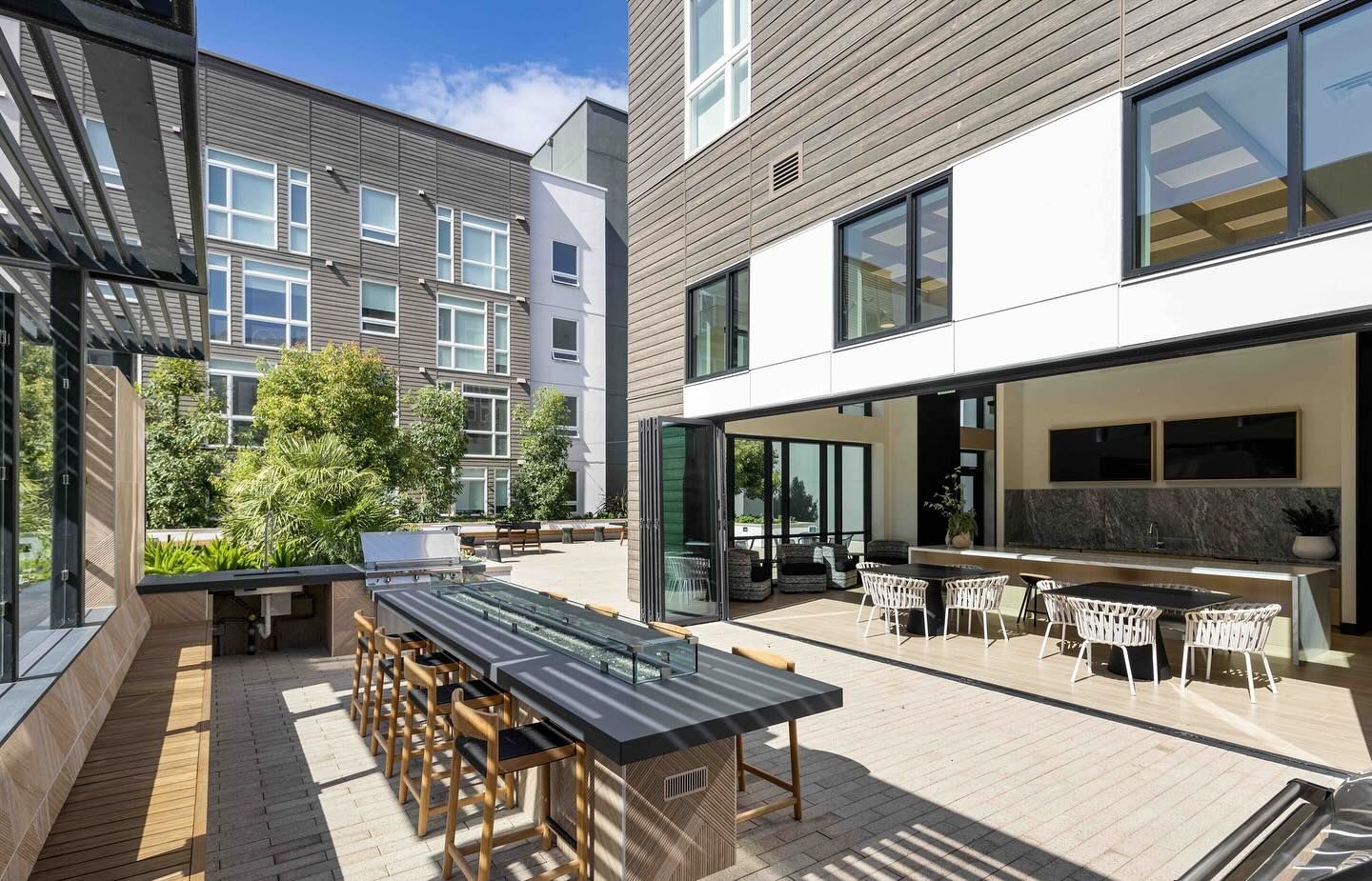 An artist 's impression of a patio area with a table and chairs in front of a building.