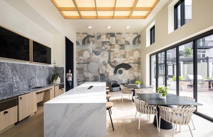 A kitchen with a large island , tables and chairs.