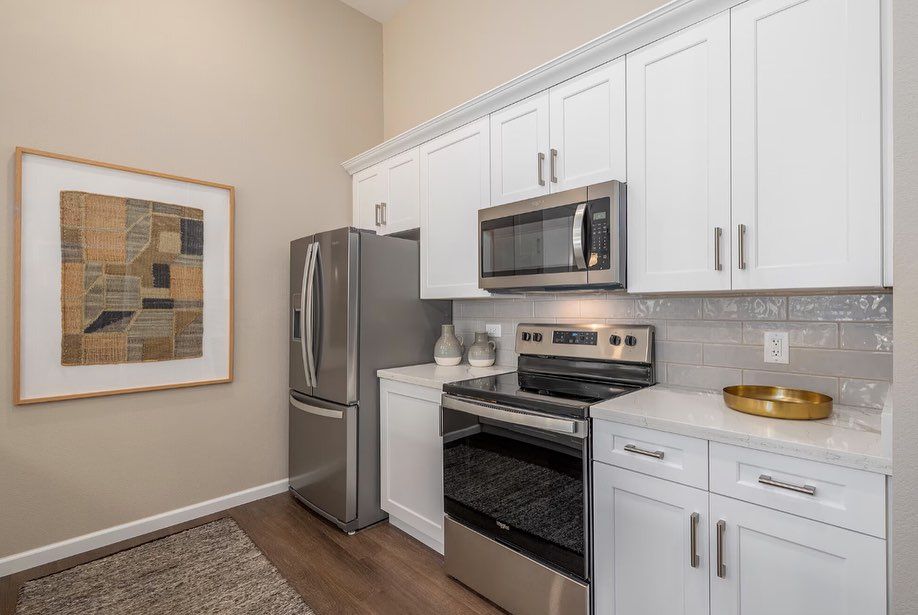 A kitchen with stainless steel appliances and white cabinets.