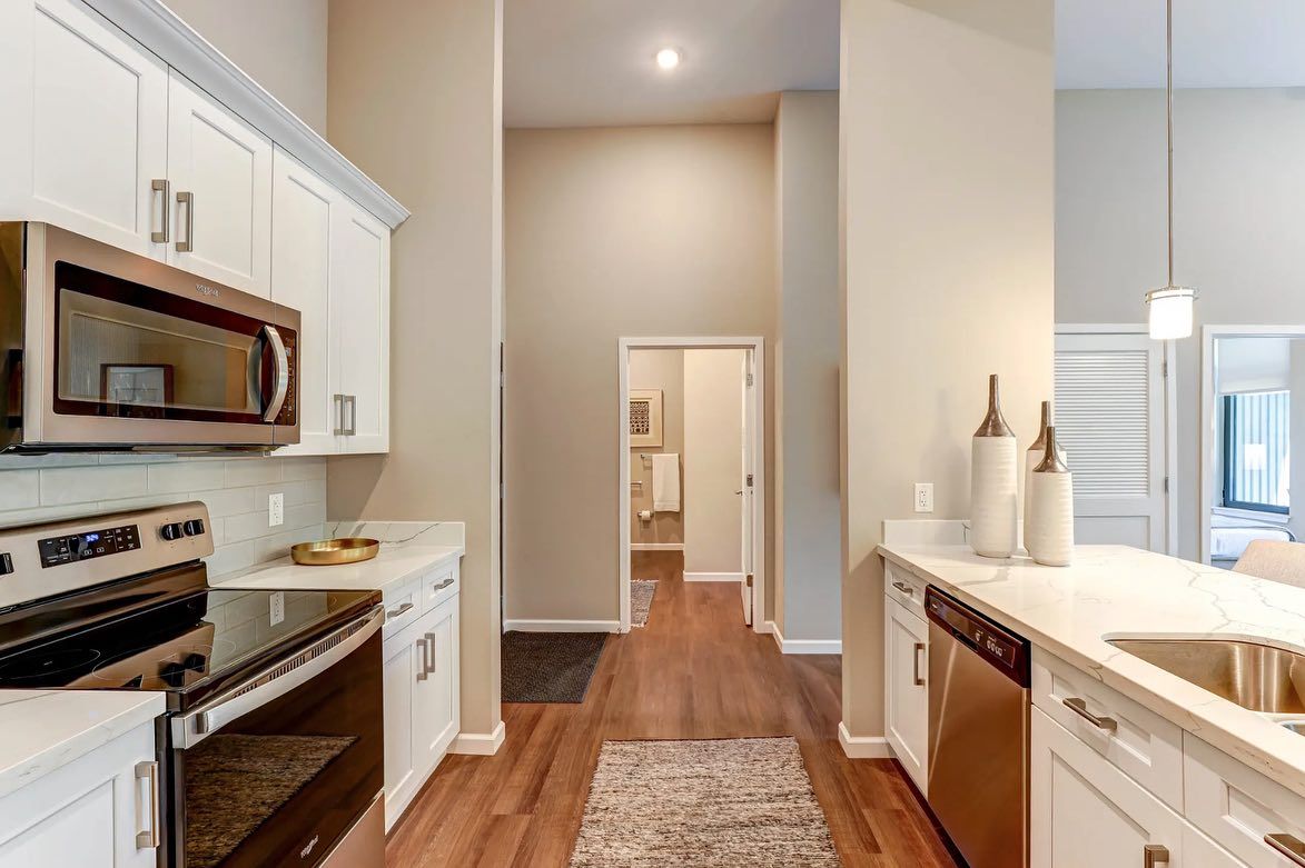 A kitchen with white cabinets , stainless steel appliances , a microwave and a sink.