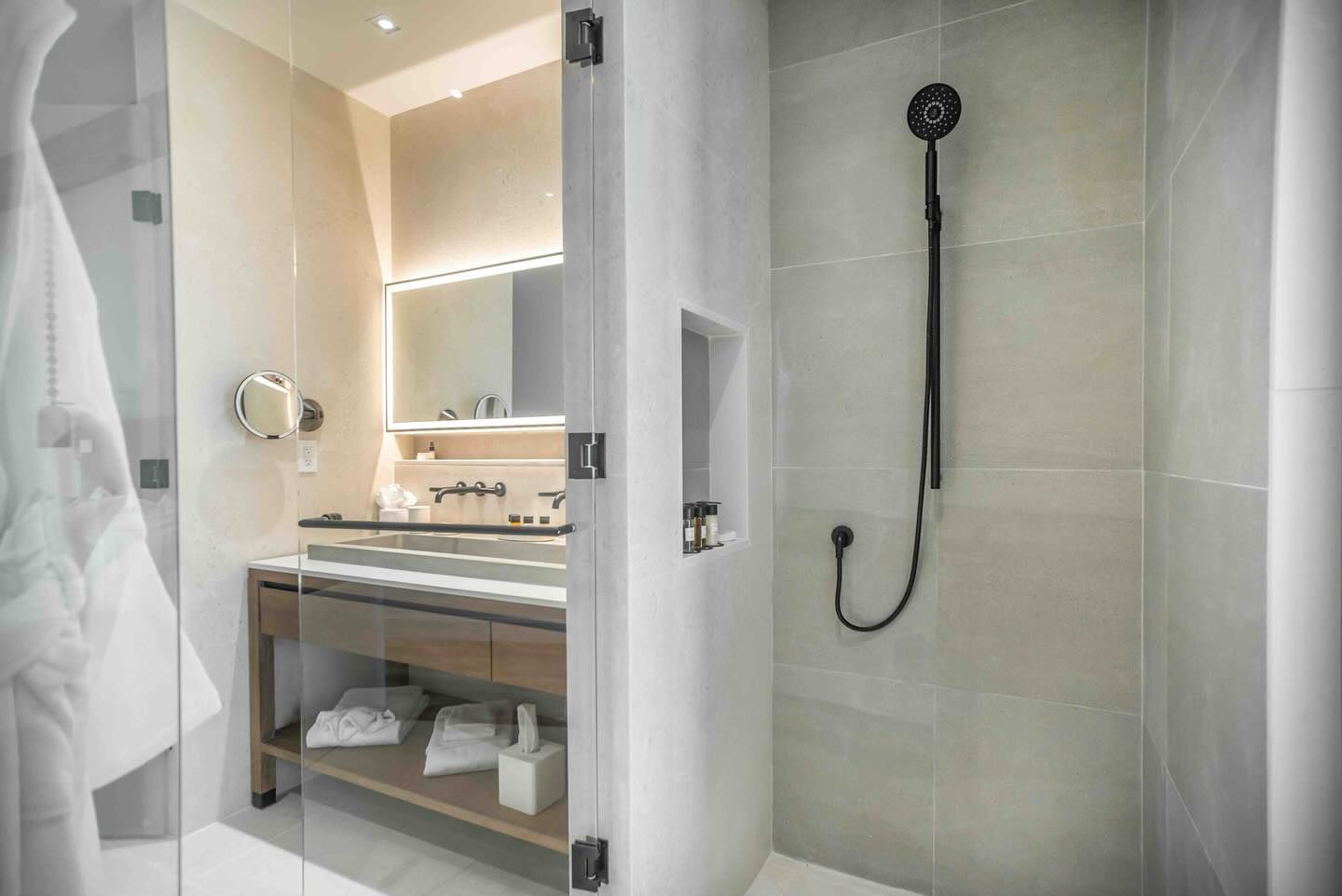 A bathroom with a walk in shower , sink and mirror.
