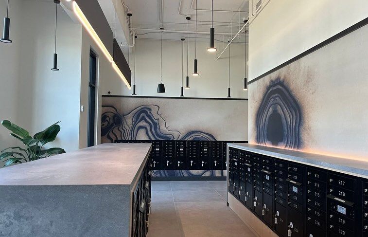 A room with a painting on the wall and a row of mailboxes.