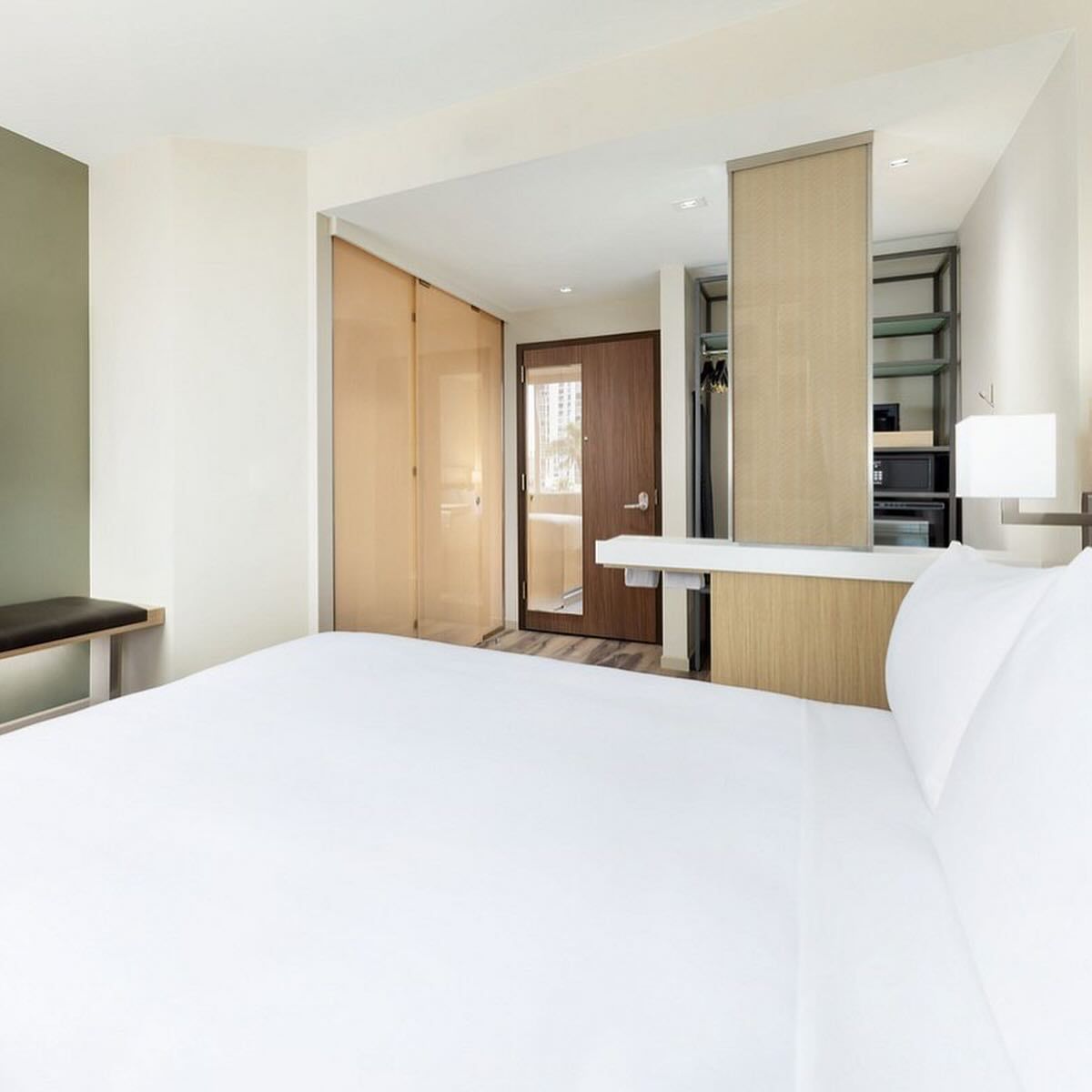 A hotel room with a king size bed and a bench