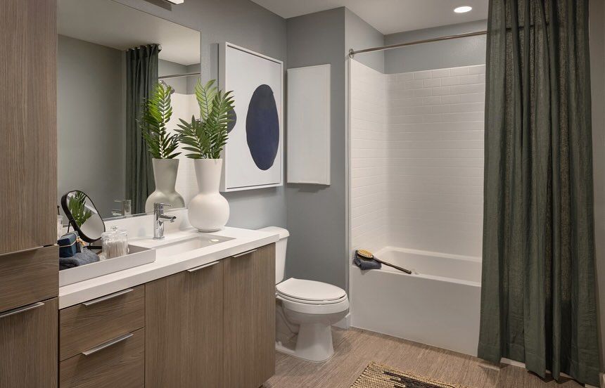 A bathroom with a toilet , sink , mirror and bathtub.