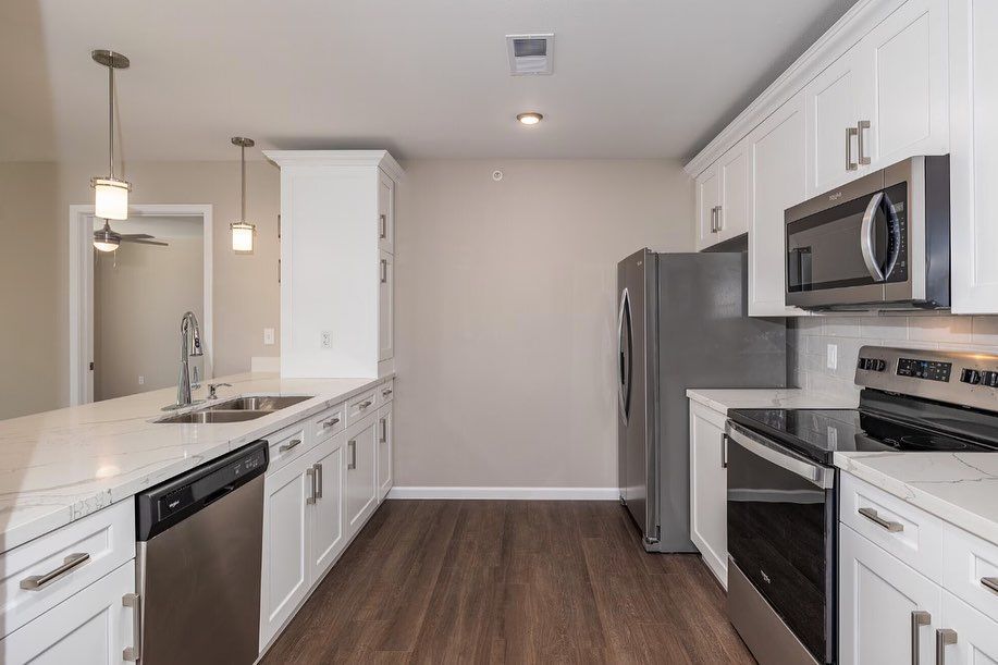 A kitchen with stainless steel appliances and white cabinets.