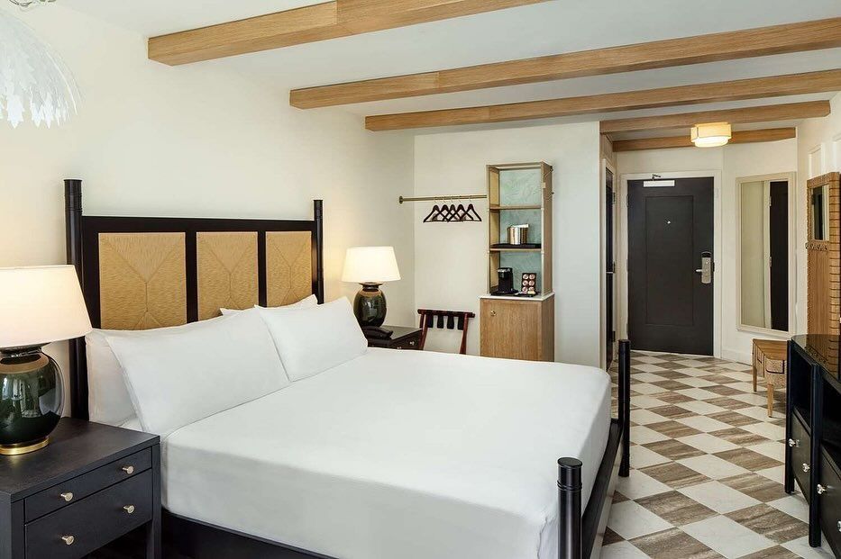 A hotel room with a king size bed and a checkered floor.