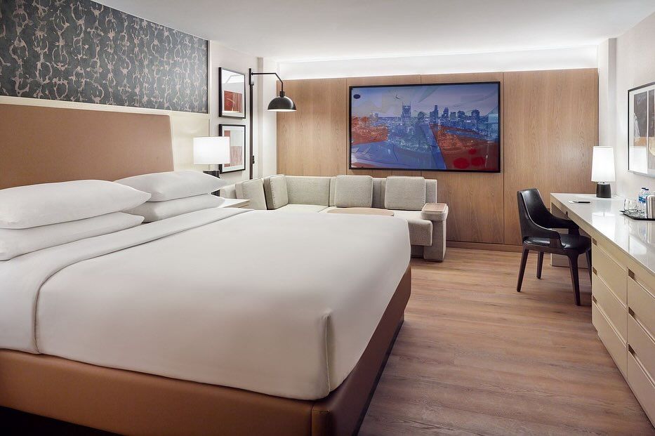 A hotel room with a king size bed , couch , desk and television.