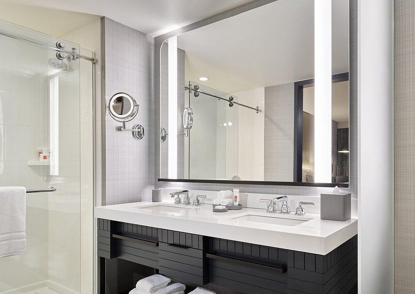 A bathroom with two sinks , a mirror and a shower.